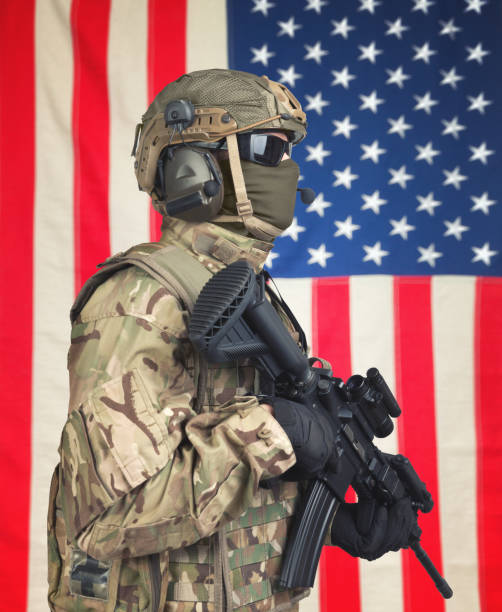 istock US soldier with machine gun in hands and American flag on background 674980512