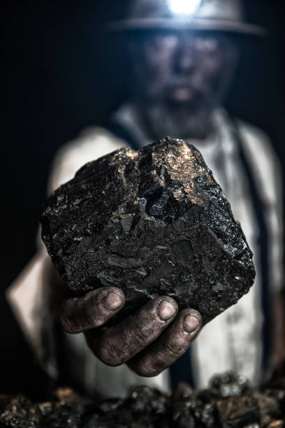 istock Dirty coal miner offering a large piece of Anthracite coal 674997584
