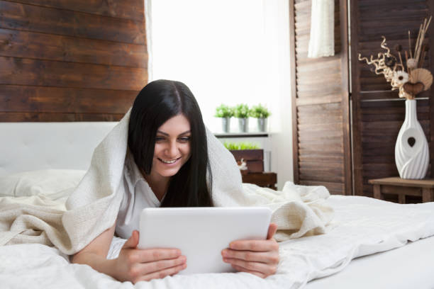istock Beautiful woman relaxing on the bed and using her tablet 675003176