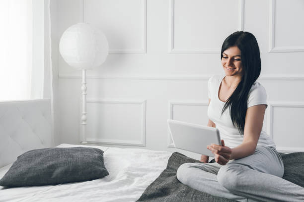 istock Beautiful woman relaxing on the bed and using her tablet 675003270
