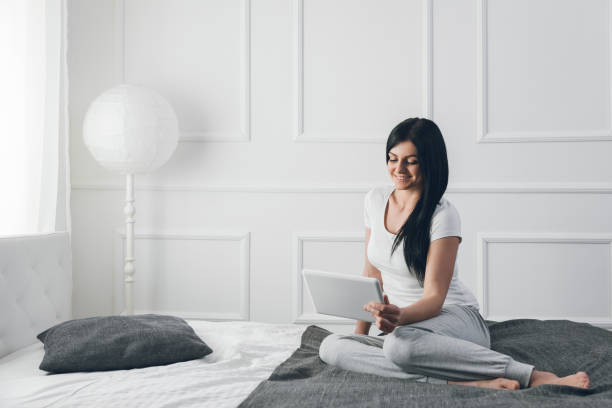 istock Beautiful woman relaxing on the bed and using her tablet 675003344