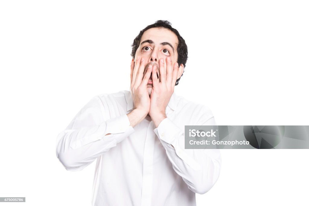 A man closing his mouth with his big hands A man who wears white shirt closing his mouth with his big hands Men Stock Photo