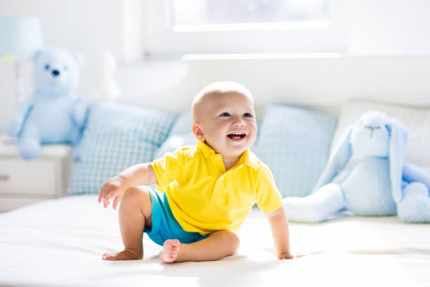 istock Baby boy playing on bed in sunny nursery 675010090