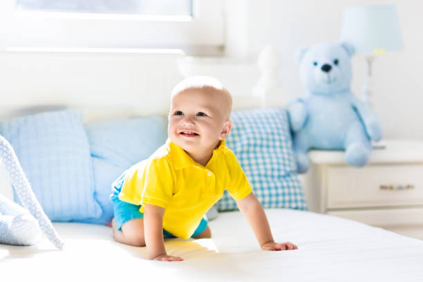 istock Baby boy playing on bed in sunny nursery 675011552