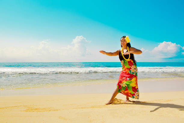 Hawaiian Hula Dancer Dancing on the Beach A beautiful Hawaiian Hula dancer dancing on the beach of the tropical Hawaiian islands. She is wearing a traditional Hula dance dress with a lei and a head dress. Photographed in horizontal format with copy space in Kauai, Hawaii. hula dancer stock pictures, royalty-free photos & images