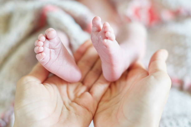 istock Mother holding newborn baby's feet in her hands 675017458