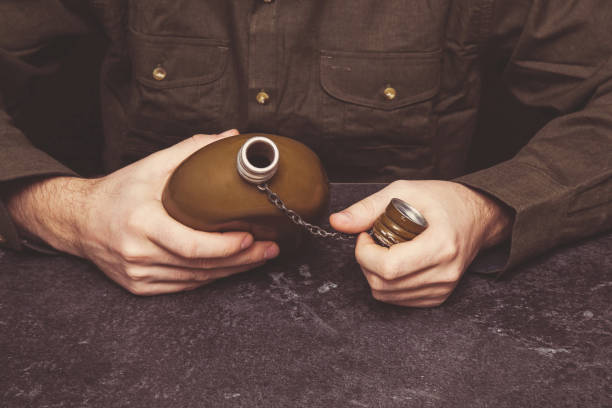 man's hands holding a military drinking flask. vintage retro style. - addiction ammunition weapon army imagens e fotografias de stock