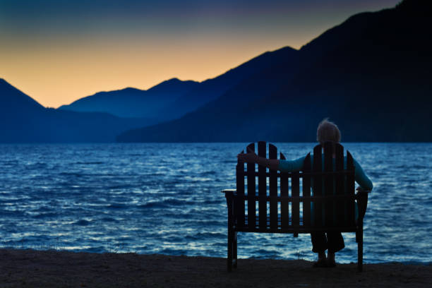 Lonely Depressed Divorced Widowed Woman Silhouette at Sunset A lonely woman sitting by herself by a lake at sunset. Concept photo of loneliness, depression, divorce, or widowed. Looking toward a brighter future. Photographed at Lake Crescent, Olympic National Park in Washington State. USA olympic peninsula photos stock pictures, royalty-free photos & images