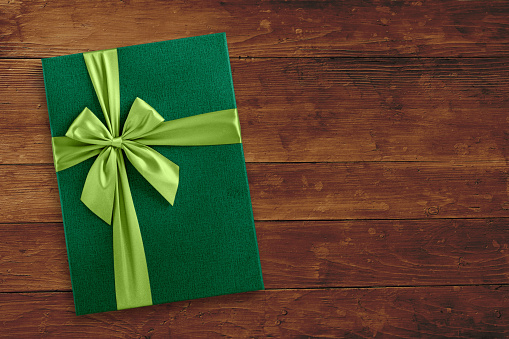 Green gift box on wood, holiday background, top view