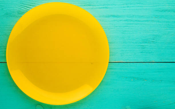 istock plate on a wooden background.yellow plate. plate top view. copy space 675044704