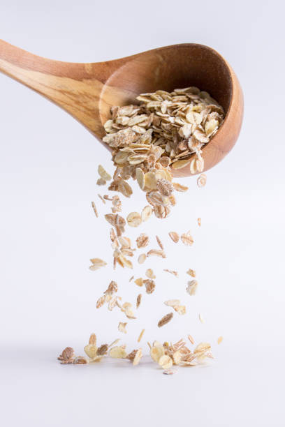Spoon of oatmeal falling on a white background, isolated