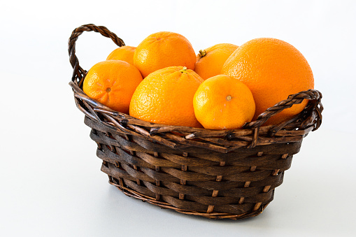 closeup of a basket of oranges and mandarins on a white background