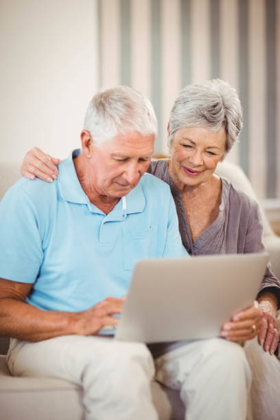 istock Senior man using laptop in living room 675051752