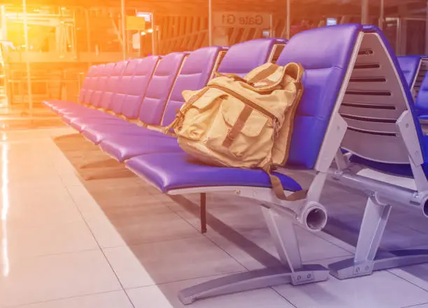 Backpack Cream color put on the blue chair In Airport background.Image is made with orange light color filters.