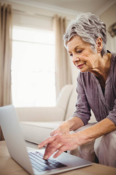 istock Senior woman using laptop in living room 675051930