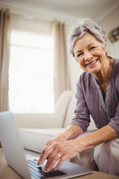 istock Senior woman using laptop in living room 675051962
