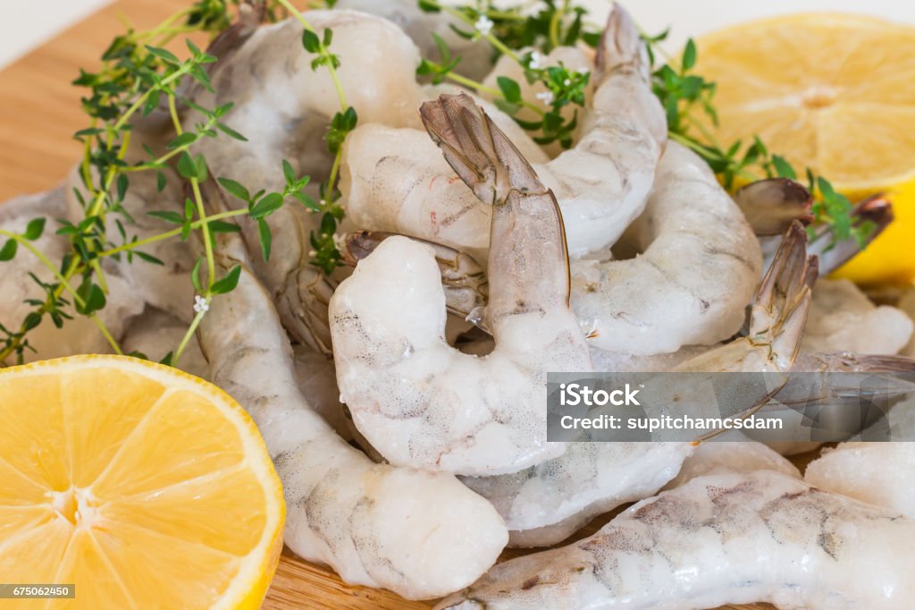 Frozen raw Shrimp Frozen raw Shrimp With Tails on wooden cutting board Shrimp - Seafood Stock Photo