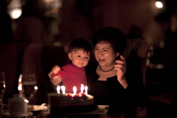 retrato íntimo de asia abuela y niño nieto celebrando cumpleaños con velas alrededor de un pastel - enzo fotografías e imágenes de stock