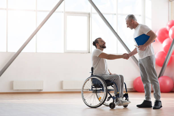 istock Cheerful disabled patient greeting his physical therapist in the gym 675062944