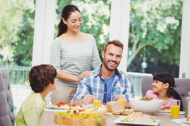 istock Smiling family with mother standing at dining table 675062994
