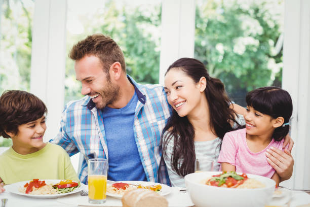 istock Smiling family with arm around while sitting at dining table 675063638