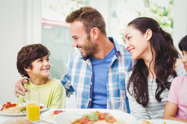 istock Smiling parents looking at son at dining table 675063818