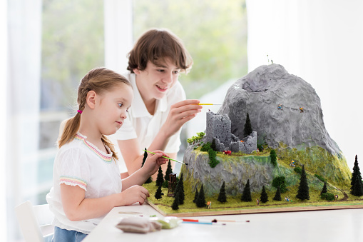 Children work on model building school project. Kids build miniature scale model mountain for geography class. Extracurricular activities and hobby club. Art and crafts for teenager and preschool.