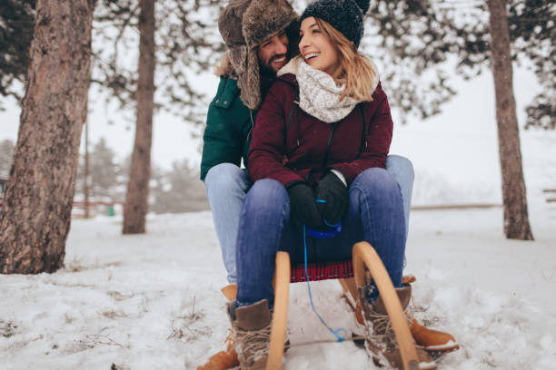 istock Smiling couple sledding in a winter day 675068502