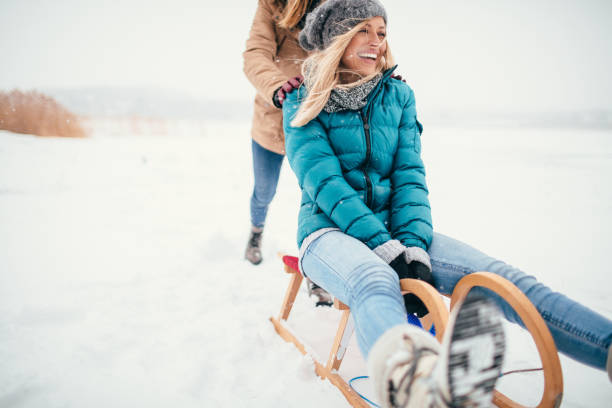 dos amigas trineos en un día de invierno - deslizarse en trineo fotografías e imágenes de stock