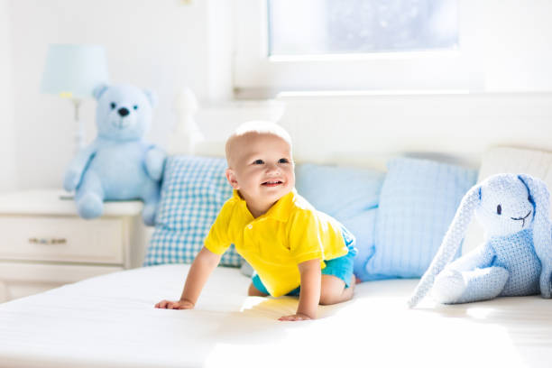 istock Baby boy playing on bed in sunny nursery 675073100