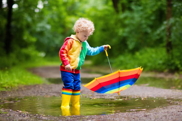 istock Child playing in the rain under umbrella 675074804