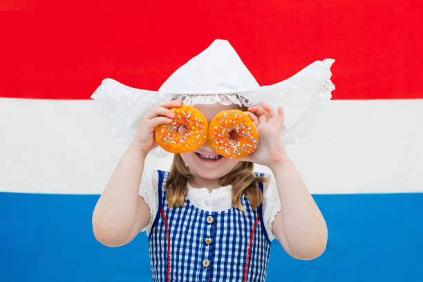 istock Dutch girl with orange donuts and Netherlands flag 675076936