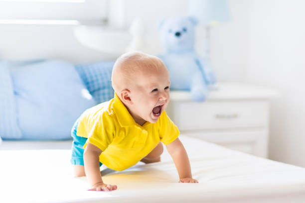 istock Baby boy playing on bed in sunny nursery 675077010