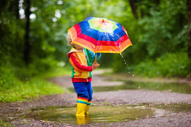 istock Child playing in the rain under umbrella 675078540