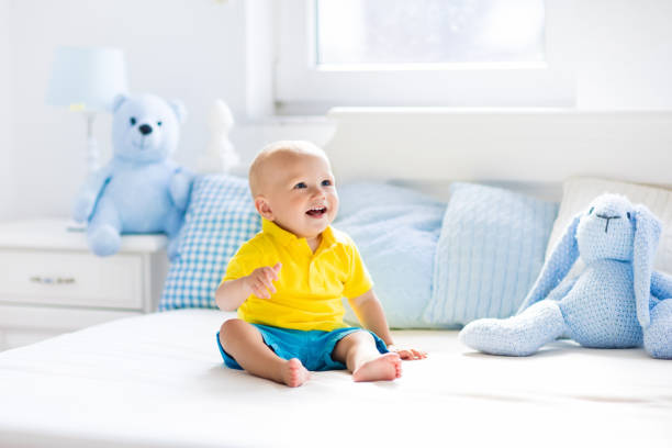 istock Baby boy playing on bed in sunny nursery 675079280