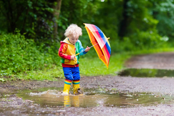 istock Child playing in the rain under umbrella 675079450