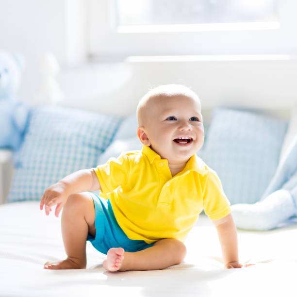 istock Baby boy playing on bed in sunny nursery 675079556