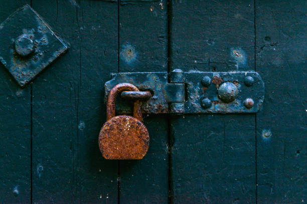 istock Old rusty padlock on wooden doors, old green destroyed door,safety 675080582