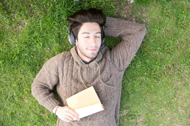 istock Young man daydreaming on the grass in the park 675080850