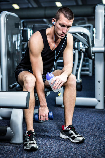istock Muscular man with headphones lifting dumbbells 675090582