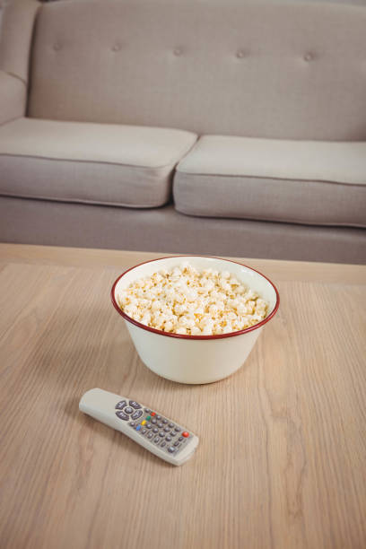 istock Bowl of popcorn and television remote on table 675090932