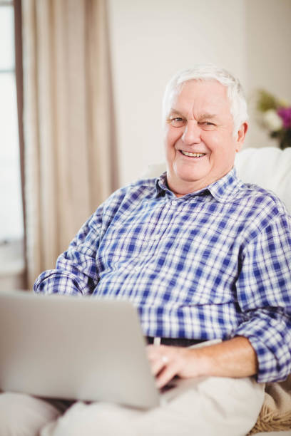 istock Senior man using laptop in living room 675091496