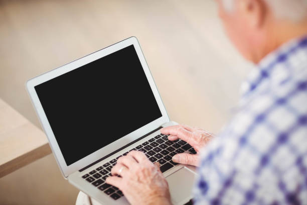 istock Senior man using laptop in living room 675091500