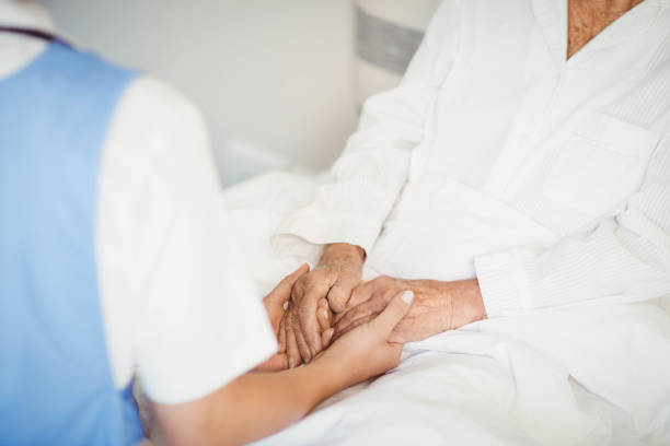 istock Senior woman and nurse holding hands 675091544
