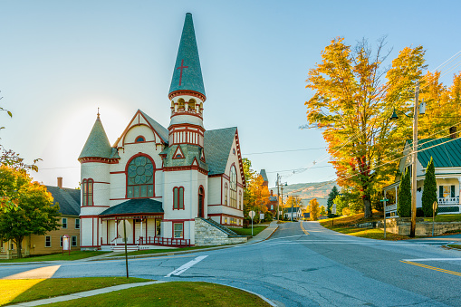 A small church in a small town Ludlow in Vermont in the autumn. The sunset brightens the leaves and church looks even more beautiful
