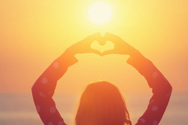 istock Girl making a heart-shape for the sunset / sunrise. 675097144