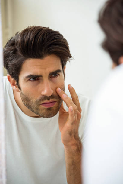 istock Man checking his skin in bathroom 675172104