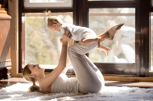 Joven atractiva yogui madre y bebé hija haciendo ejercicio en hom photo