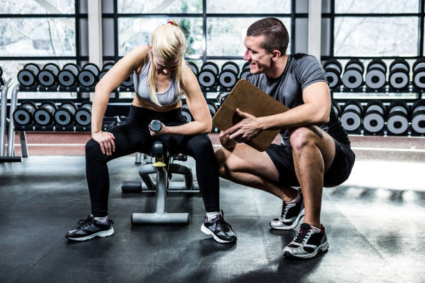 istock Fit woman doing dumbbells exercise with trainer 675176792