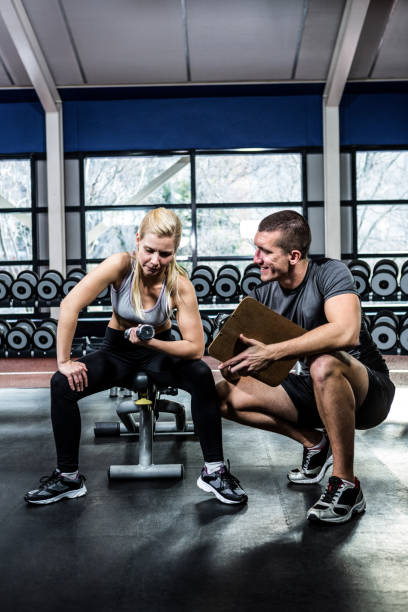 istock Fit woman doing dumbbells exercise with trainer 675176826